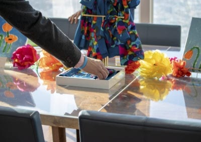 a man's hand reaching for a colorful scarf in a white box